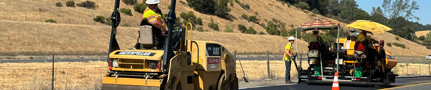 construction vehicles and workers paving a road
